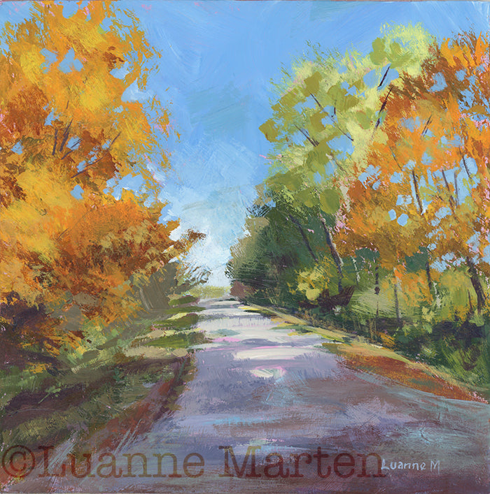 Painting of a road flanked by trees in bright fall foliage of oarnges, gold, green, signed 'Luanne Marten'.